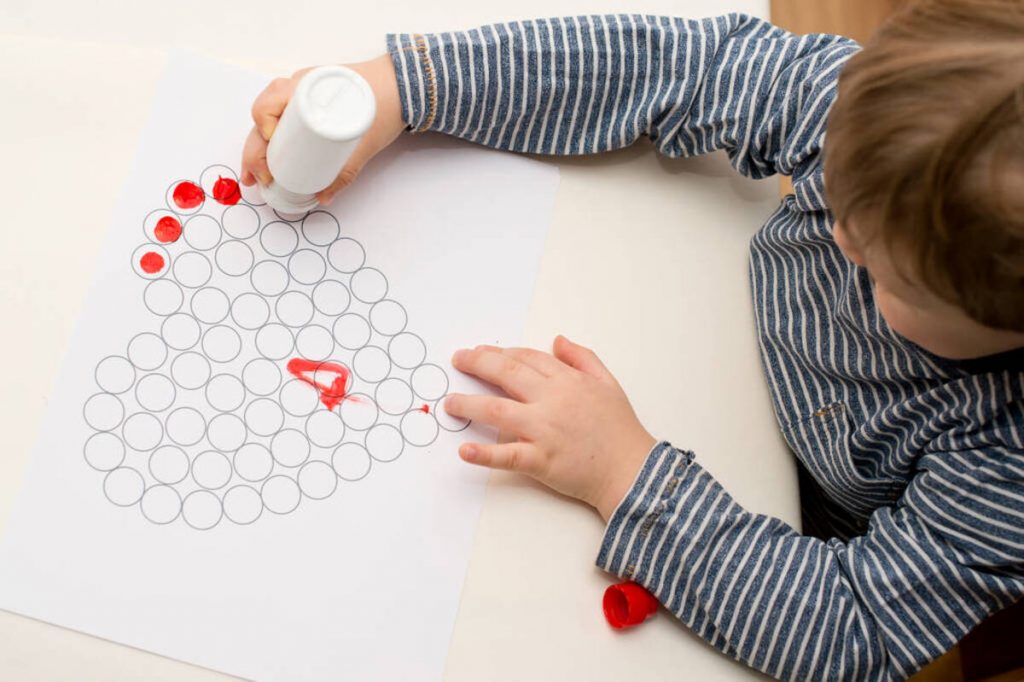 Jeune garçon colorie un dessin en forme de cœur