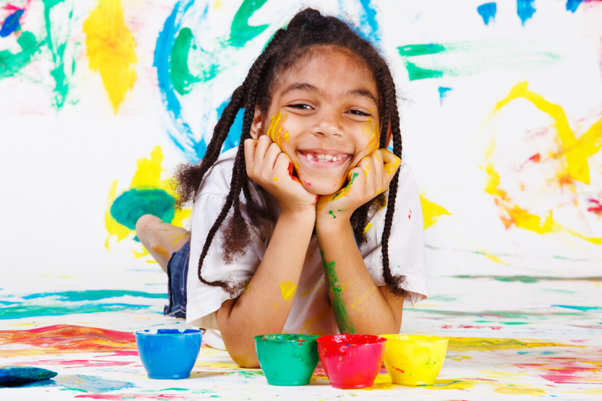 Jeune fille souriante devant des pots de peinture