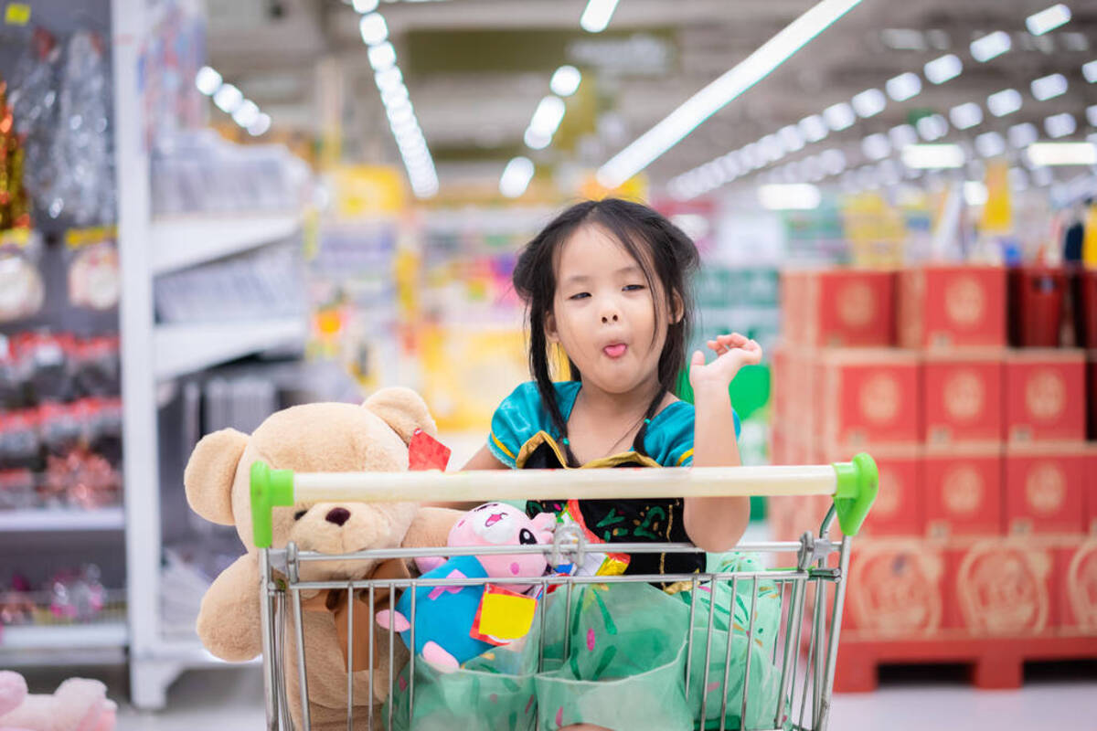 Petite fille contente devant un panier de jouets enfants